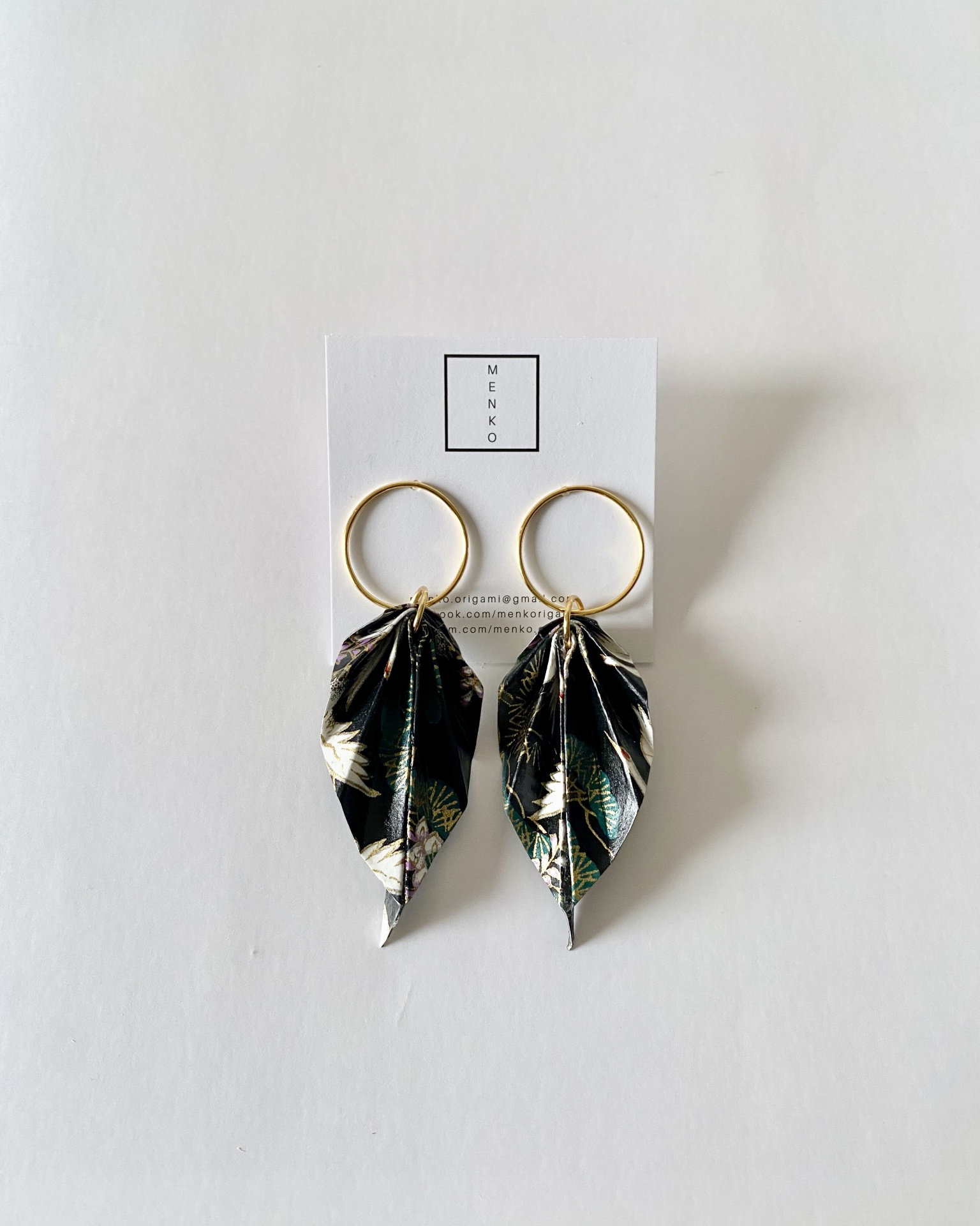 Brincos Folha Brincos dourados com pendentes em forma de folha estampados em preto e branco sobre cartão MENKO