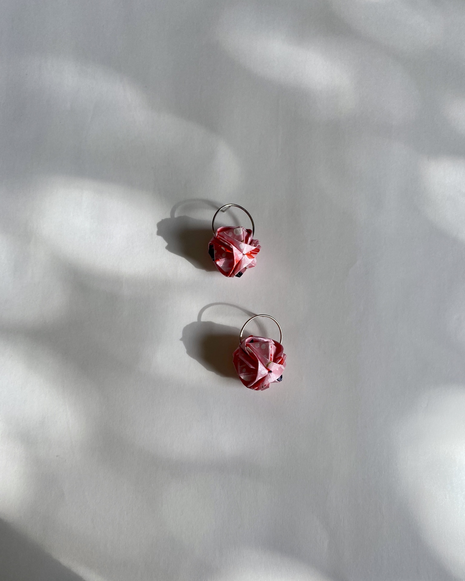 Brincos Barun Brincos de aro com flores vermelhas e brancas sobre fundo branco com sombras