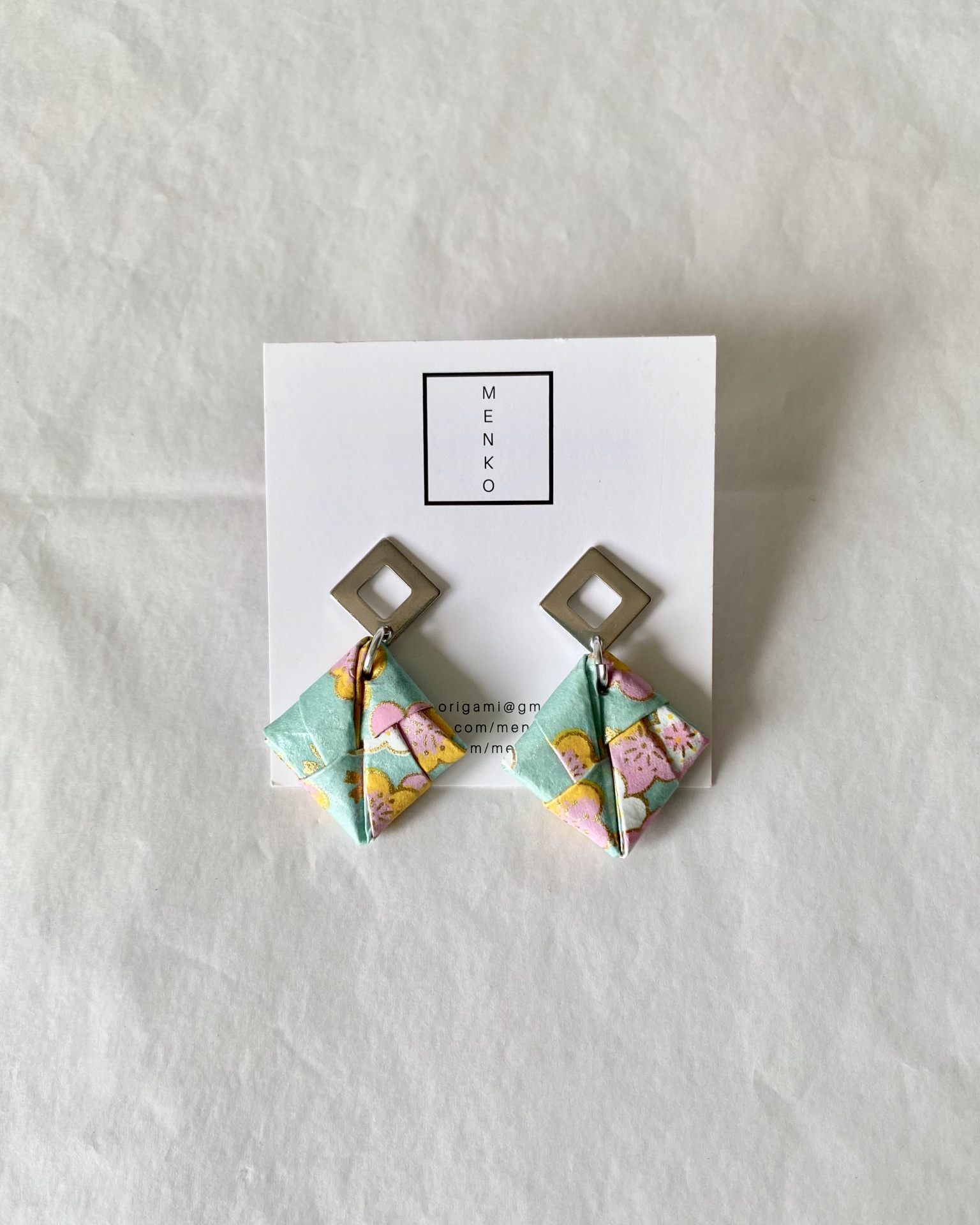 Brincos Sonobe Brincos quadrados em metal com pendente origami floral em verde, amarelo e rosa em cartão branco MENKO.
