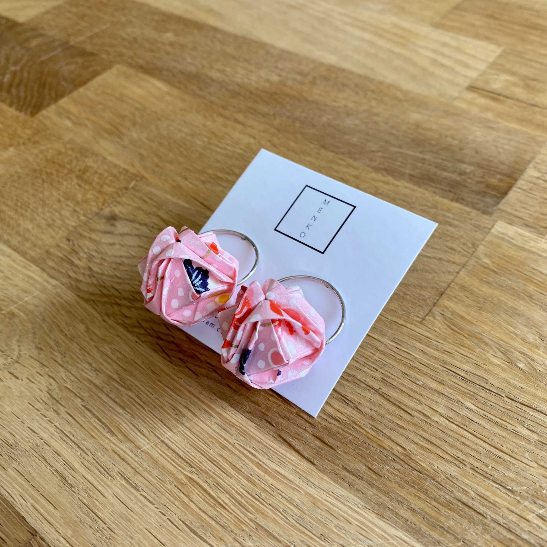 Brincos Barun Brincos com argola prateada e laço de tecido rosa com padrão colorido, sobre cartão branco