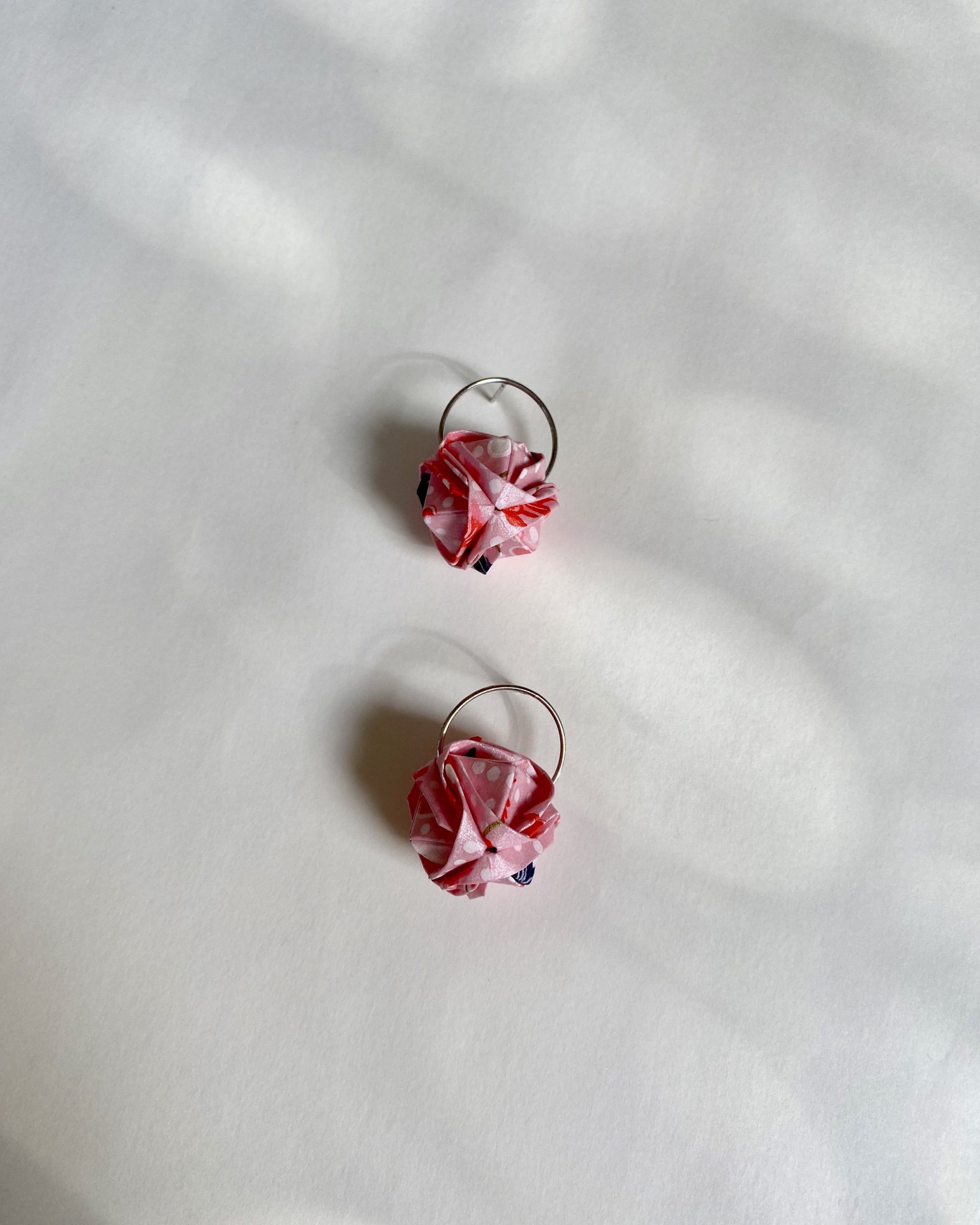 Brincos Barun Argolas de metal com tecido rosa e padrões coloridos sobre fundo branco