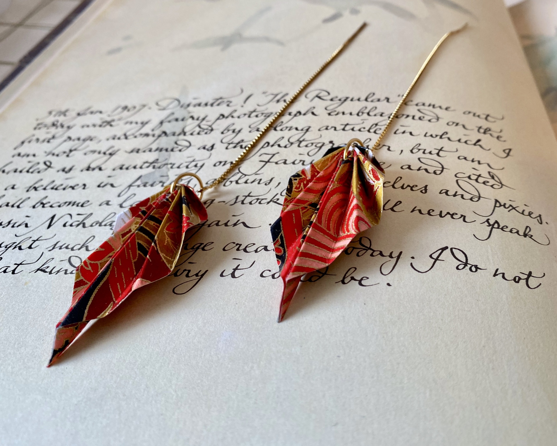 Brincos Folha Brincos pendentes em tecido colorido sobre texto manuscrito
