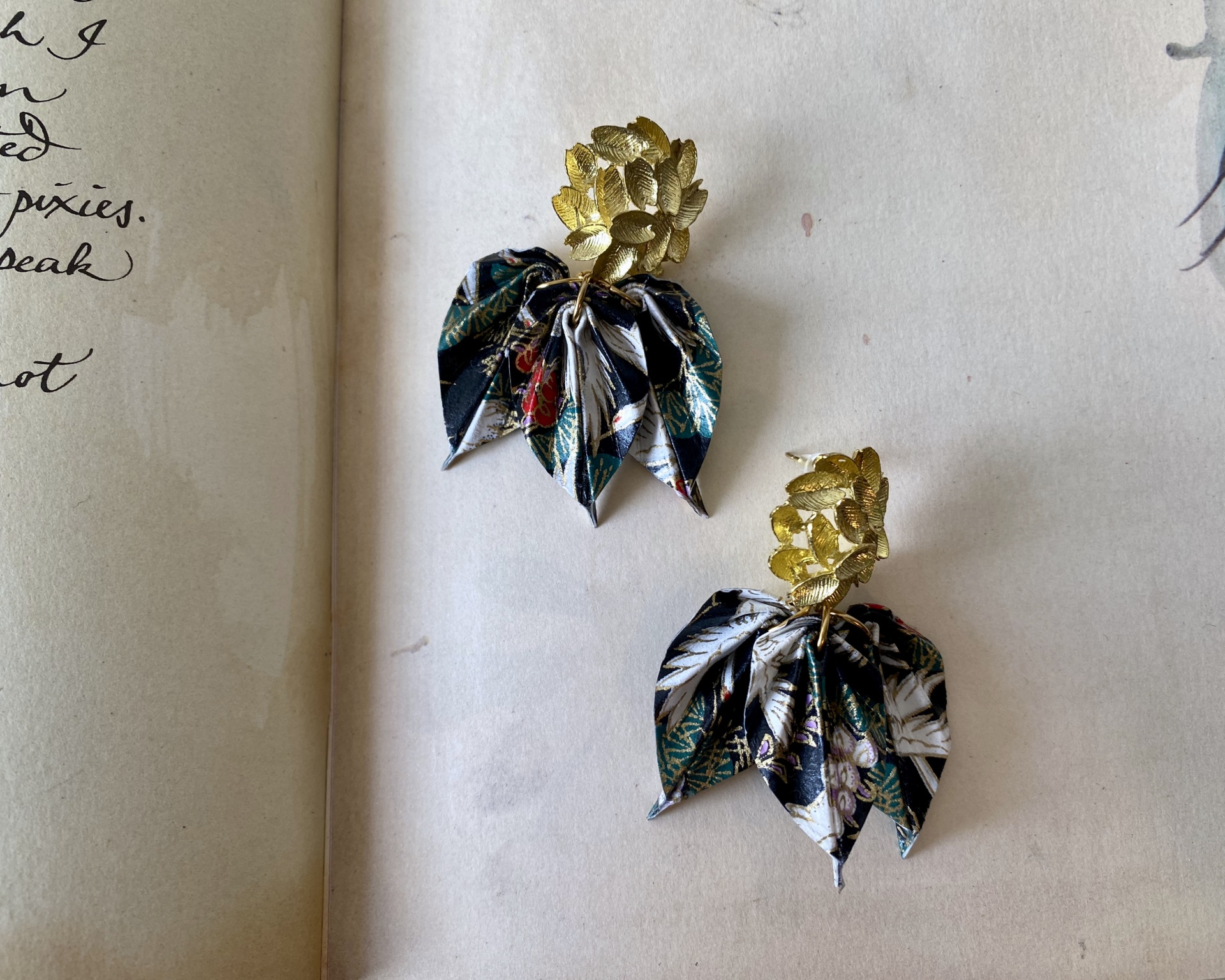 Brincos Folha Brincos com folhas douradas e tecido estampado sobre página de livro