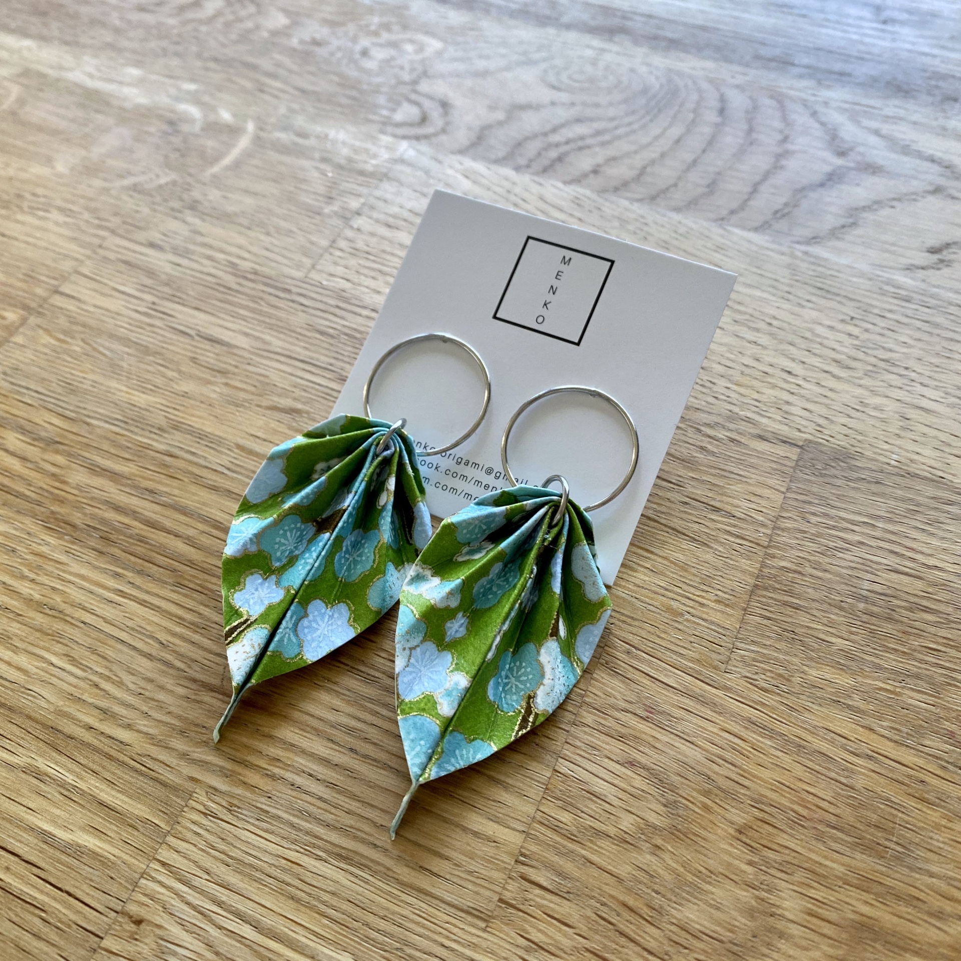 Brincos Folha Brincos de tecido verde e azul em formato de folha pendurados em argolas prateadas sobre cartão WENKO