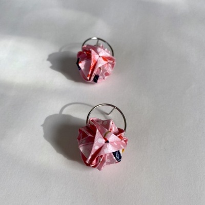 Brincos com flores de tecido rosa e padrão floral sobre superfície branca