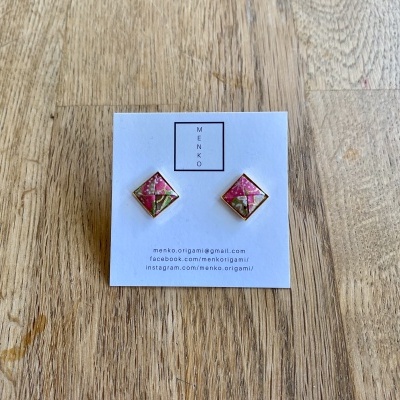 Brincos quadrados rosa e verde apresentando em cartão branco sobre madeira clara