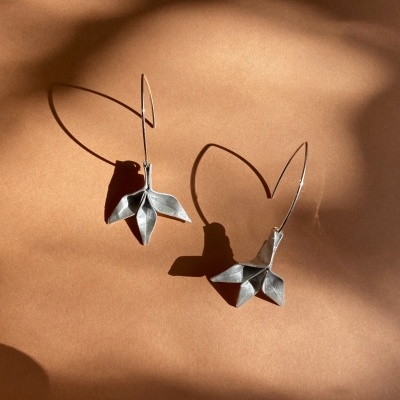 brincos de prata com design em forma de folha sobre fundo castanho claro