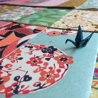 Papéis decorativos coloridos com padrões florais e geométricos e origami azul