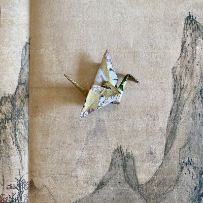 Origami de papel floral dourado sobre fundo com desenho de montanhas