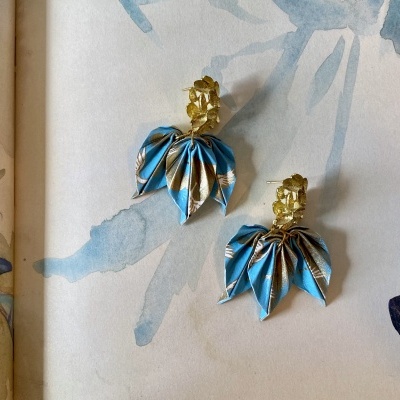 Brincos com base dourada e pendentes de tecido azul com padrão dourado