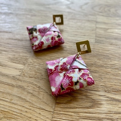 Brincos quadrados com tecido floral rosa e fecho dourado sobre madeira clara