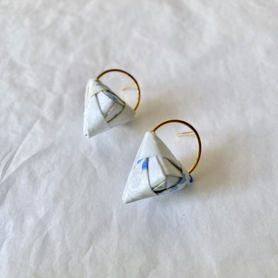 Brincos com argolas douradas e pendentes triangulares em papel branco com padrão azul e cinza