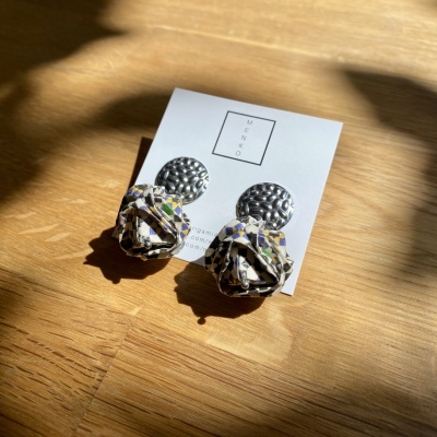 Brincos com topo metálico prateado texturizado e pendente em tecido colorido sobre cartão branco MEKO