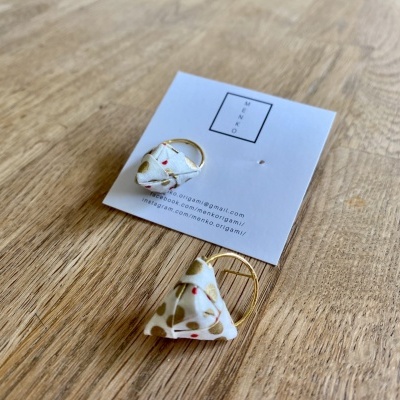 Par de brincos triangulares em tecido com padrão de pontos sobre cartão branco