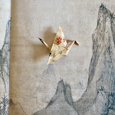 Origami de ave em papel decorado sobre fundo com desenho de montanhas