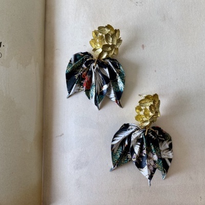 Brincos com folhas douradas e tecido estampado sobre página de livro