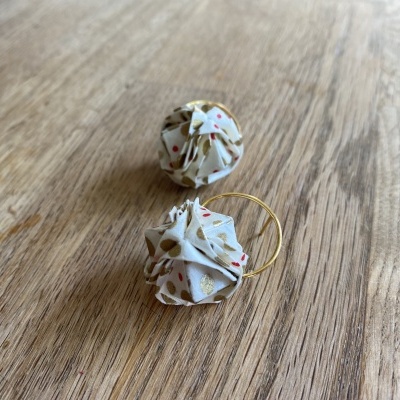 Brincos com ornamento em tecido com padrão floral sobre madeira clara