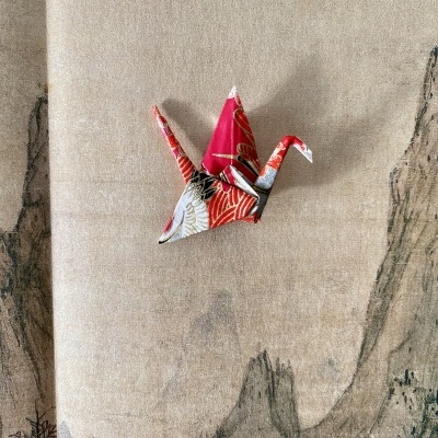 Moinho de papel origami multicolorido sobre tecido bege com desenho de montanhas