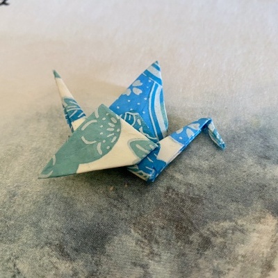 Origami de papel azul com padrão floral sobre superfície cinza
