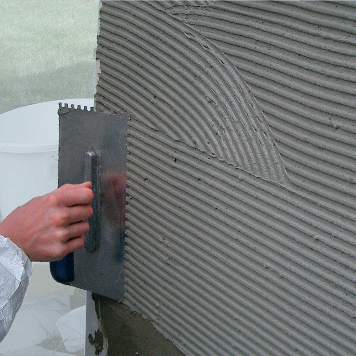 OTTOFLEX® - Argamassa de Impermeabilização Aplicação de argamassa texturada com talocha numa parede cinzenta