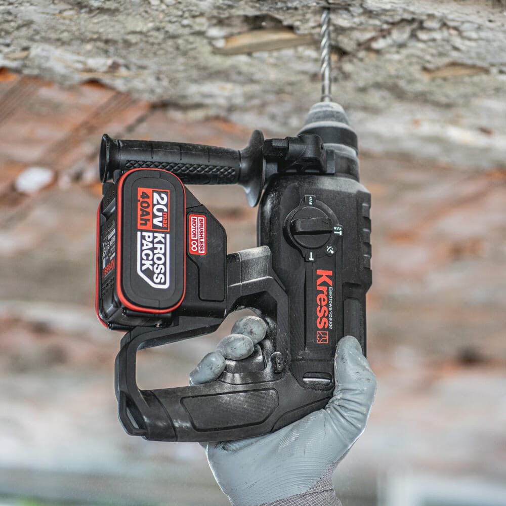 Martelo Perfurador a Bateria 20V Brushless Kress SDS-plus KUC60 Berbequim a bateria Kress preto e vermelho com broca e bateria Kross Pack 20V 4.0Ah segurado com luva cinza