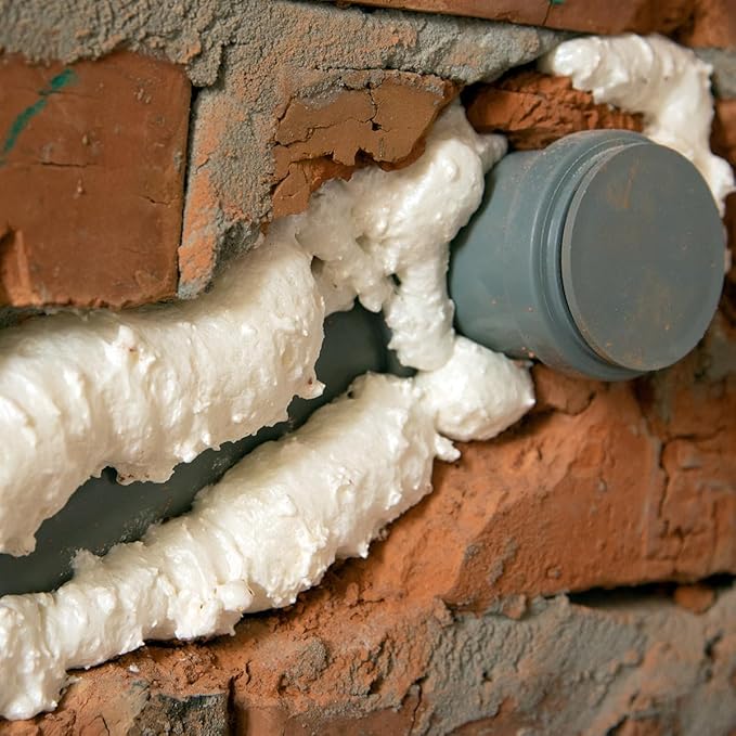 ESPUMA DE POÇOS S24 RECA | Vedação resistente para zonas húmidas Tubo cinzento numa parede de tijolos com espuma expansiva branca aplicada
