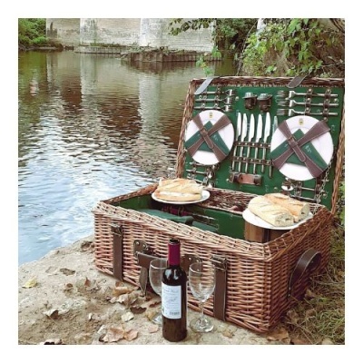 Cesta de piquenique de vime aberta junto a um rio com comida e vinho