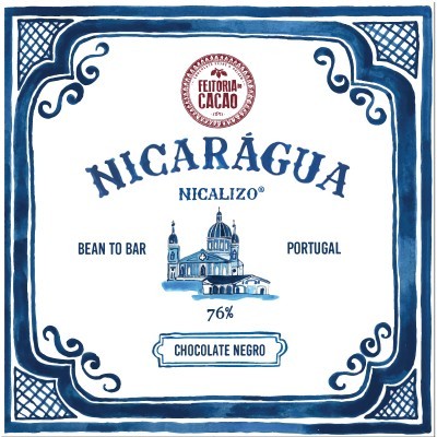 Embalagem azul e branca de chocolate negro Feitoria Cacao com 76% de cacau e ilustração de edifício.