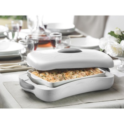 Caixa de cerâmica branca quadrada com tampa contendo lasanha numa mesa posta