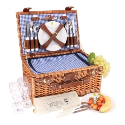 Cesto de piquenique de vime com talheres, pratos, copos e frutas