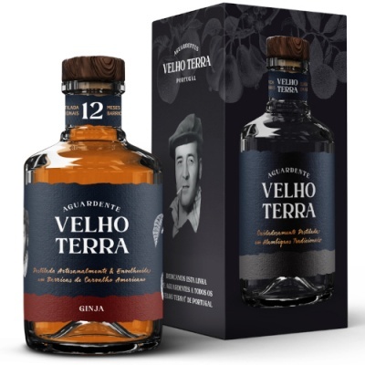Garrafa de aguardente Velho Terra com rótulo azul escuro e vermelho e tampa de madeira, ao lado de embalagem preta com foto de homem
