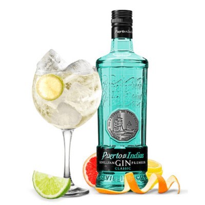 garrafa de gin verde-azulado Puerto de Indias com copo de cocktail e frutas