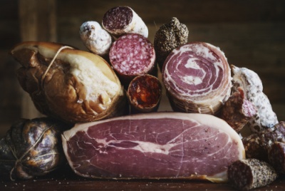 Enchidos, presunto e pão rústico sobre tábua de madeira