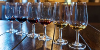 Seis copos de vinho com vinho tinto e branco numa mesa de madeira