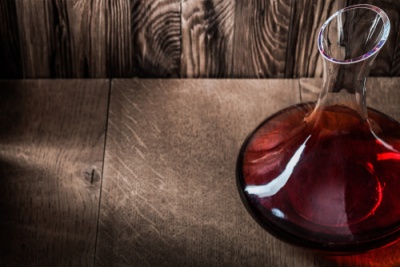 Garrafa de vidro com líquido vermelho sobre superfície de madeira