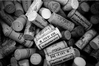 Várias rolhas de cortiça usadas com diferentes marcas e textos, em imagem a preto e branco.