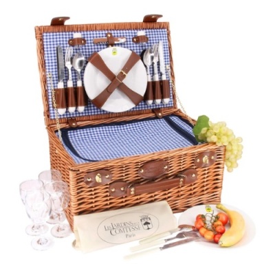 Cesto de piquenique de vime com talheres, pratos, copos e frutas