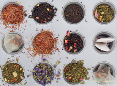 Doze taças brancas com vários tipos de chá solto, flores secas e saquinhos de chá numa superfície branca.