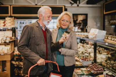Casal idoso com cesto e frasco em loja de produtos embalados