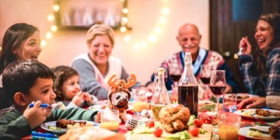 Família a jantar com cachorro vestido de rena entre a comida na mesa