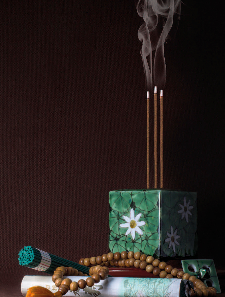 Incensário cúbico verde com flores, paus de incenso queimando, rosário de contas de madeira