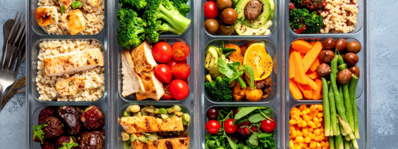 Marmitas transparentes com diversas refeições coloridas e saudáveis em fundo cinzento