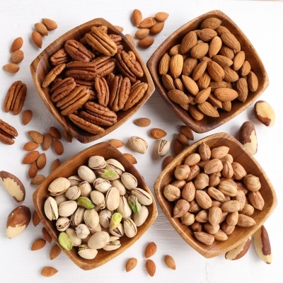 tigelas de madeira com vários tipos de nozes sobre superfície branca