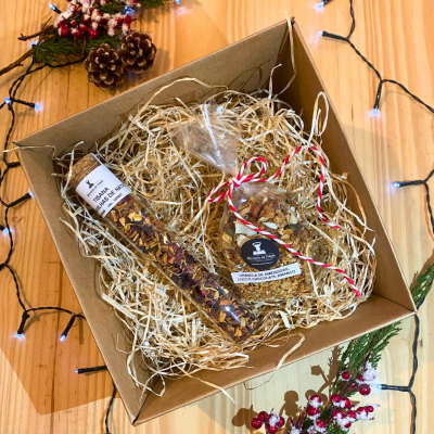 Caixa de presente com palha, granola, tubo de vidro com tisanas, luzes natalícias azuis e decoração