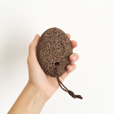 Esponja de pedra-pomes castanha com cordão segurada por uma mão