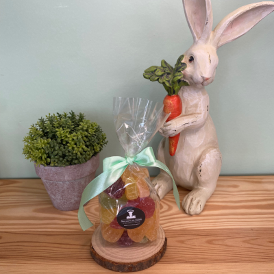 Gomas coloridas em embalagem com laço, vaso com planta, figura de coelho com cenoura