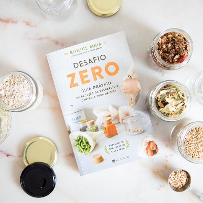 Livro 'Desafio Zero' com frascos de vidro contendo alimentos em superfície clara.