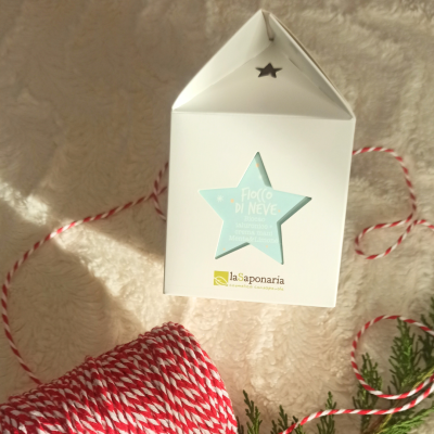 Caixa branca com estrela azul clara com texto, cordão vermelho e branco e tecido felpudo bege