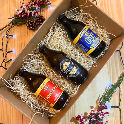Caixa com três garrafas de cerveja com etiquetas coloridas e decoração natalícia.