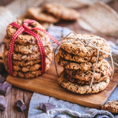 Pilhas de cookies com fita e corda em tábua de madeira com pedaços de chocolate e pano cinzento